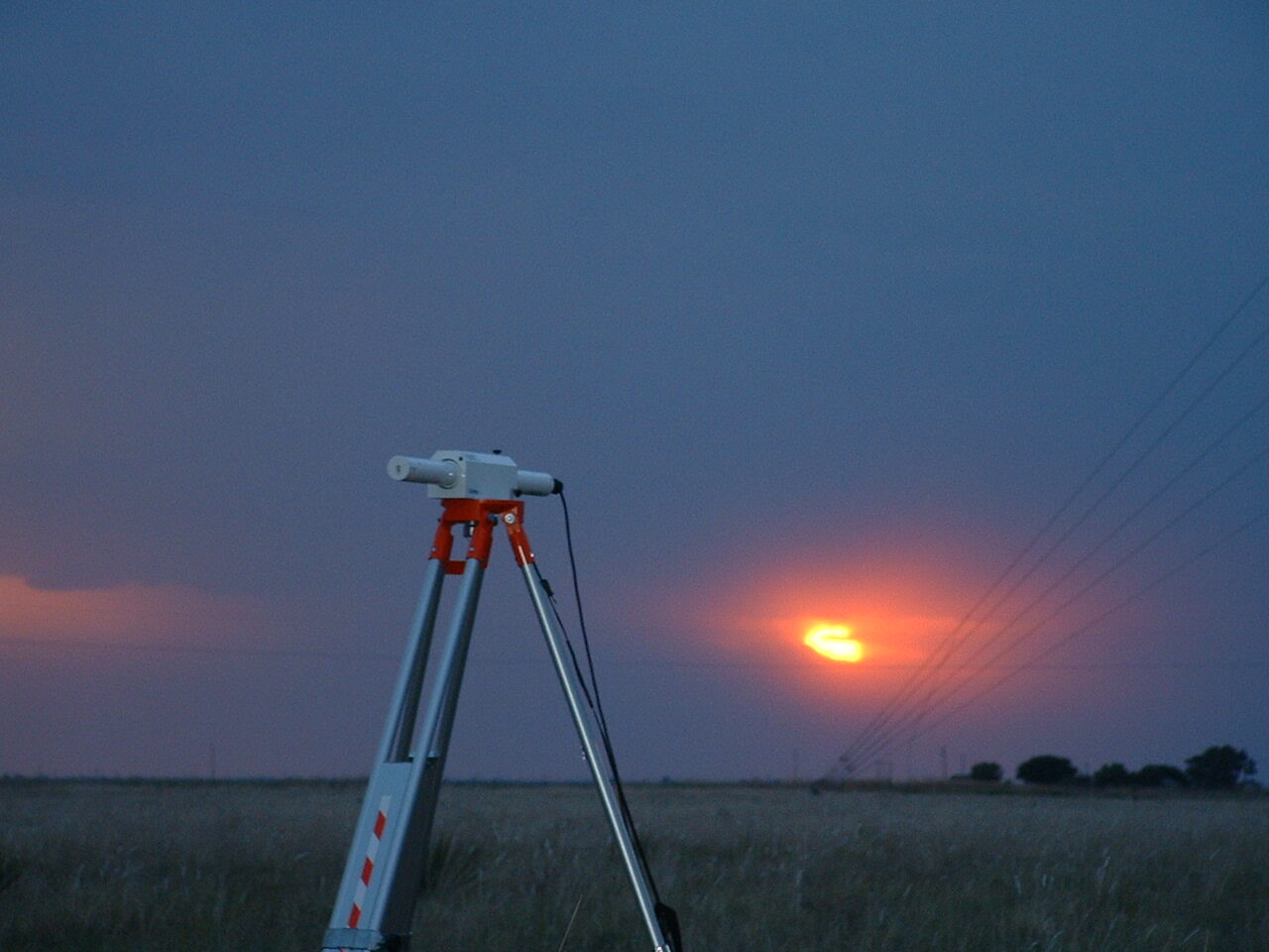 A scintillometer deployed in a field at sunset